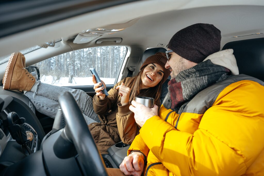 Family couple sitting in car in winter clothes in snow forest