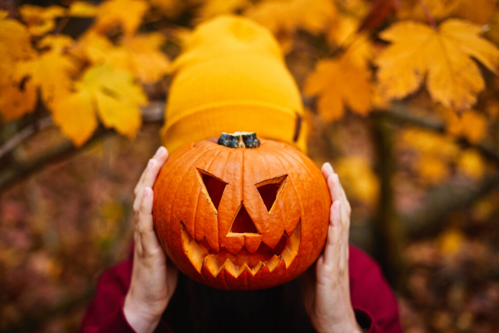 Girl holding jack-o-lantern in front of face