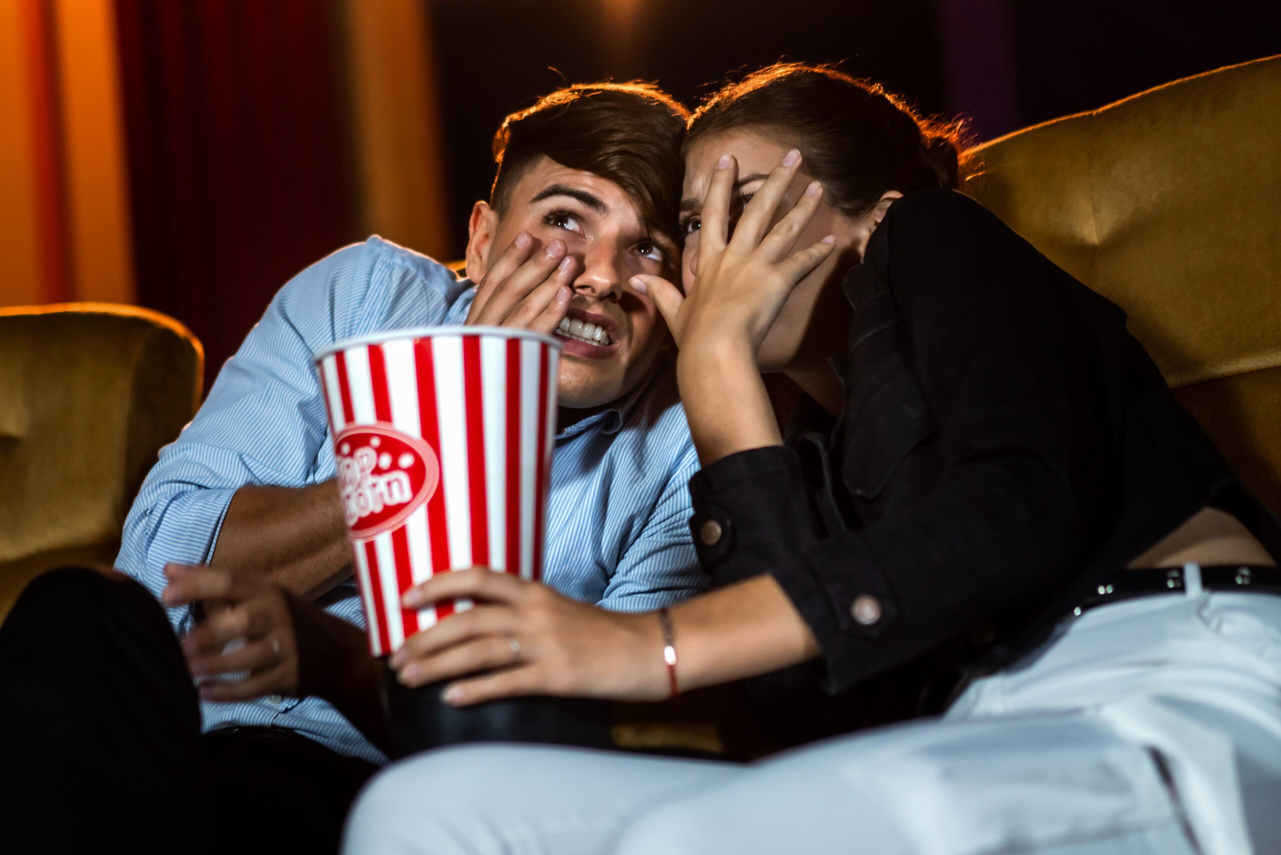 A couple watching a movie shock and eyes close in the movie theater cinema.
