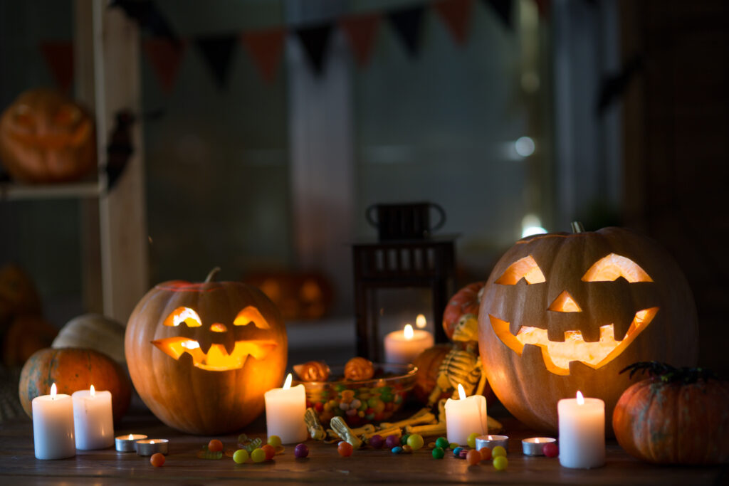 Carved pumpkins lit up on a table surrounded by candles