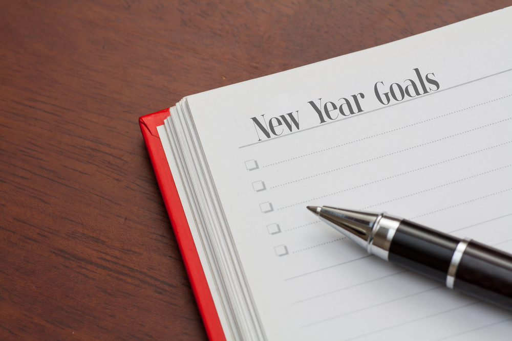 notebook on a wooden table. open diary and pen with new year goals words