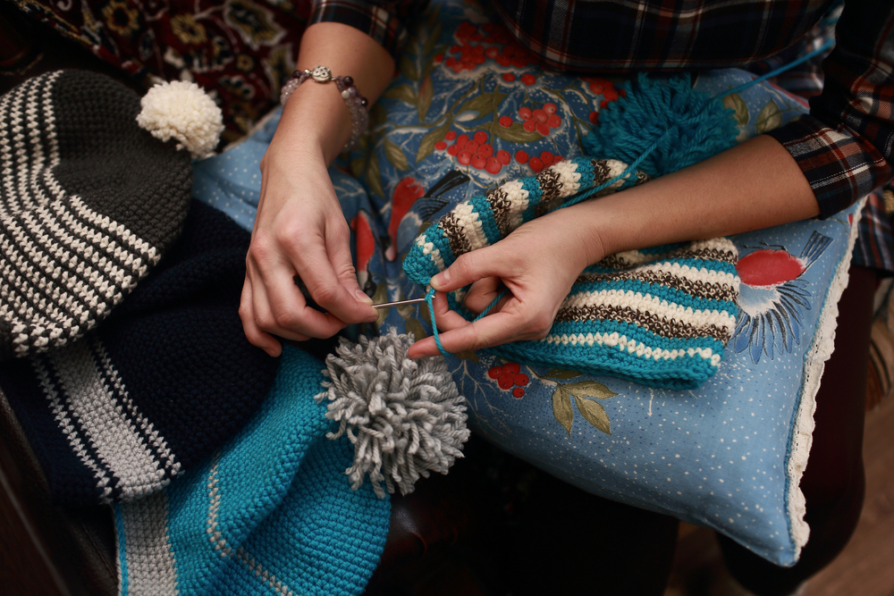 hand of a woman who crochet beanie warm of colored wool