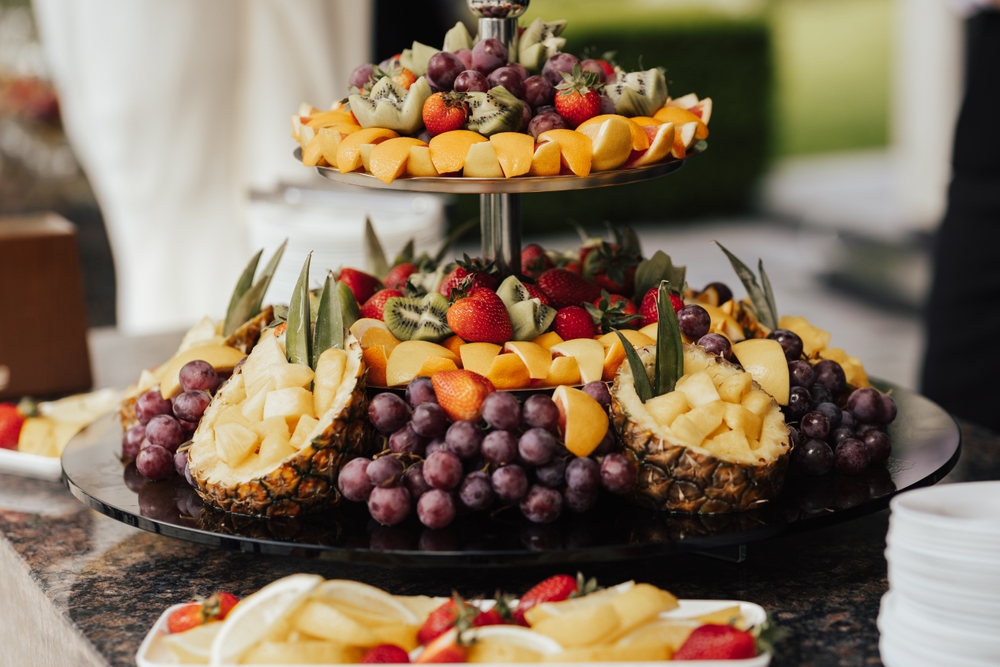 A fruit platter with pineapples, grapes, kiwi, strawberries and oranges on it.